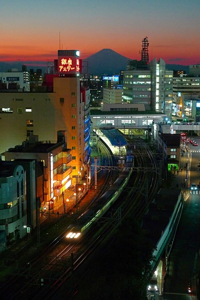 Un train quitte la gare de Fujisawa devant le mont Fuji au crépuscule