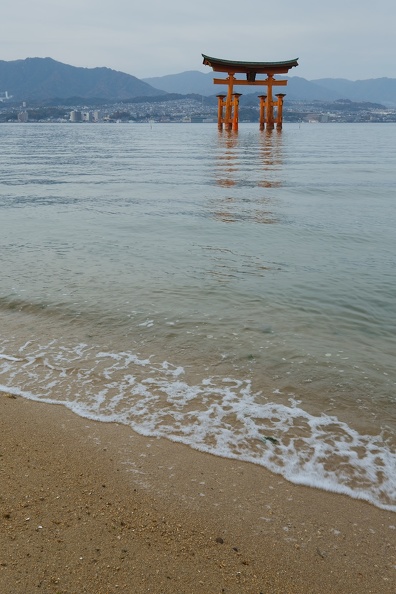 Vague s'échouant sur la plage devant le grand torii flottant d'Itsukushima
