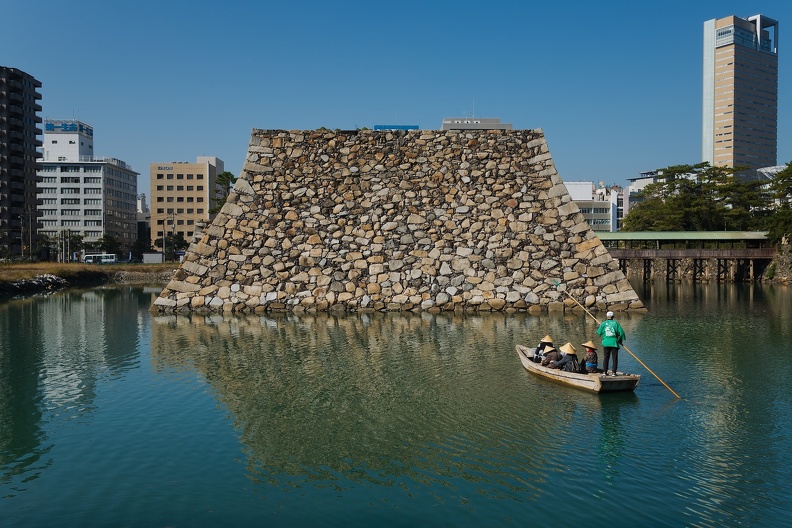 Touristes en barque portant des sugegasa et observant le château de Takamatsu
