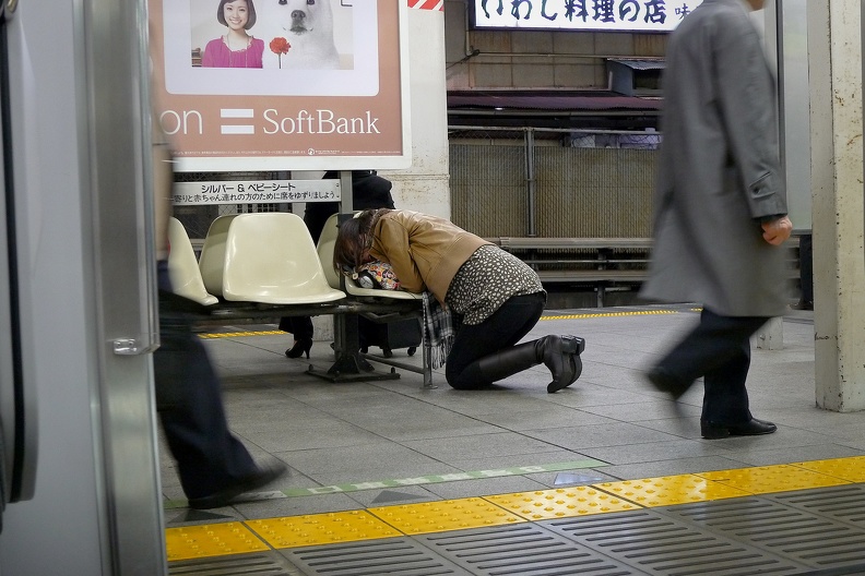 Femme dormant de fatigue sur le quai d'une station de métro à Tokyo