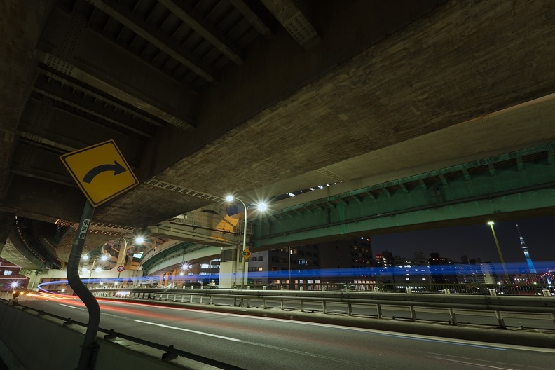 Virage serré sur un pont routier à deux niveaux et Tokyo Skytree de nuit